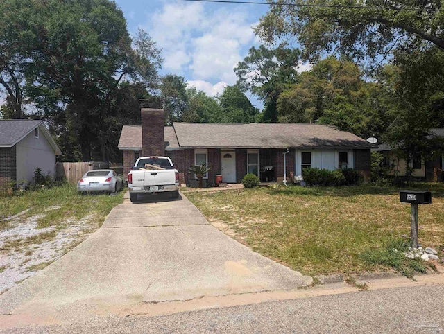 ranch-style home featuring brick siding, a chimney, concrete driveway, fence, and a front lawn