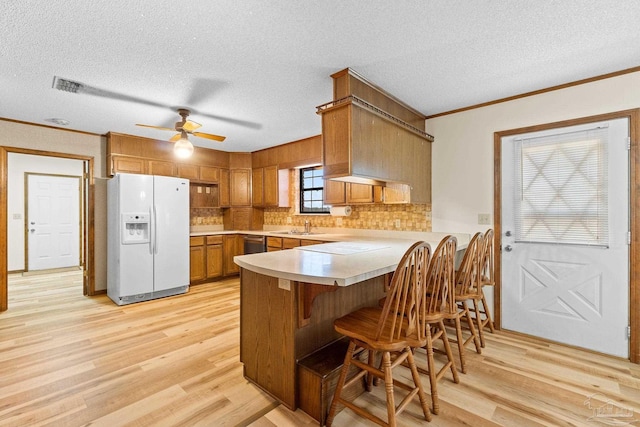 kitchen with light wood-type flooring, white fridge with ice dispenser, kitchen peninsula, and a wealth of natural light