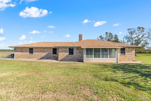 back of property with a sunroom and a lawn