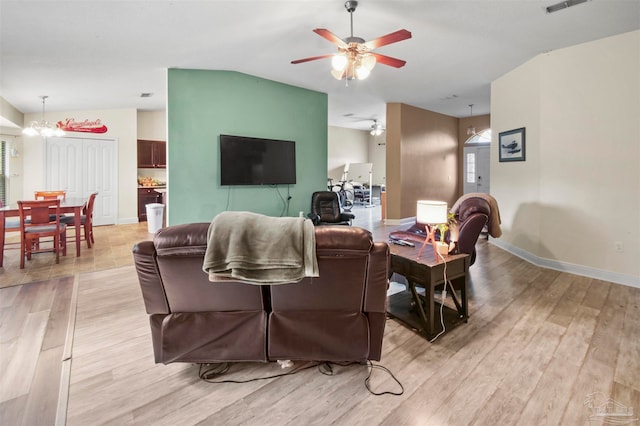 living room with ceiling fan with notable chandelier and light hardwood / wood-style floors