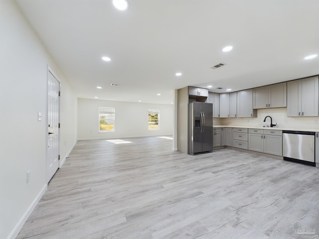 kitchen featuring appliances with stainless steel finishes, gray cabinets, light hardwood / wood-style floors, and sink