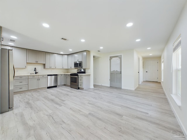 kitchen with gray cabinets, sink, appliances with stainless steel finishes, and light hardwood / wood-style flooring