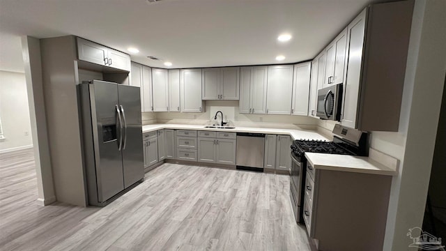 kitchen with gray cabinetry, sink, stainless steel appliances, and light wood-type flooring