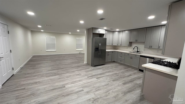 kitchen with appliances with stainless steel finishes, light wood-type flooring, gray cabinetry, and sink