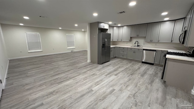 kitchen featuring gray cabinetry, sink, stainless steel appliances, and light hardwood / wood-style flooring