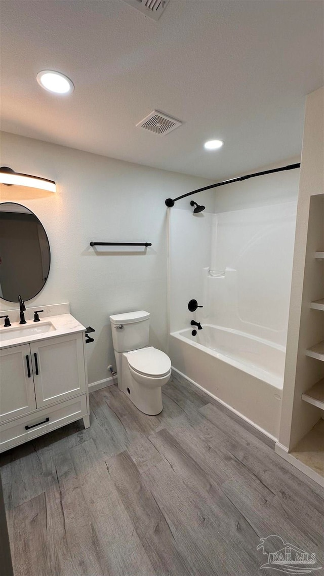 full bathroom featuring hardwood / wood-style floors, vanity, toilet, and shower / washtub combination