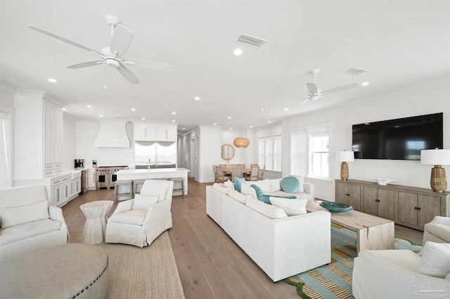 living room with light wood-type flooring and crown molding