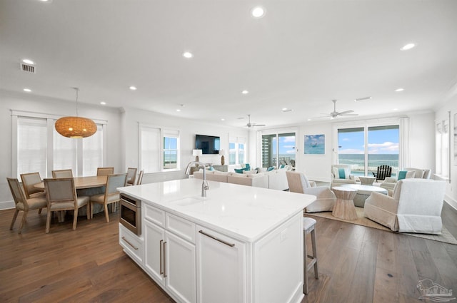 kitchen with dark wood-type flooring, a center island with sink, white cabinetry, ceiling fan, and sink