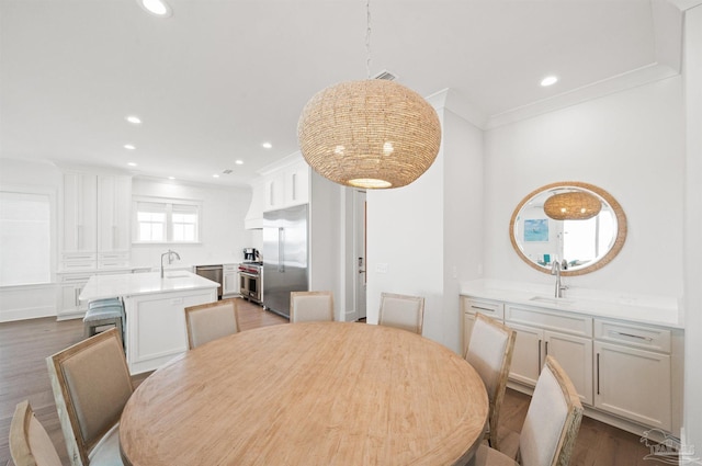 dining space with sink, dark wood-type flooring, and ornamental molding