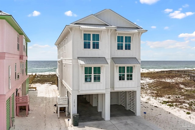 view of front of property featuring a view of the beach, a carport, and a water view