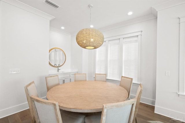 dining area featuring sink, ornamental molding, and dark hardwood / wood-style floors