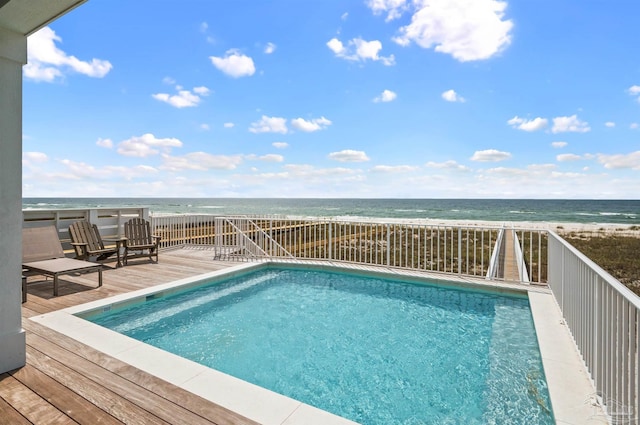 view of pool with a deck with water view and a view of the beach