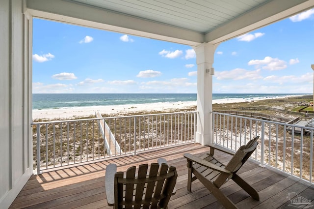 wooden deck featuring a beach view and a water view