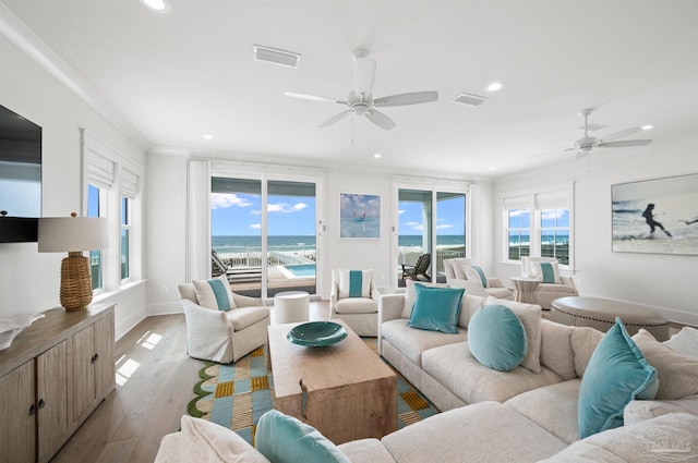 living room with ceiling fan, light hardwood / wood-style flooring, a water view, and crown molding