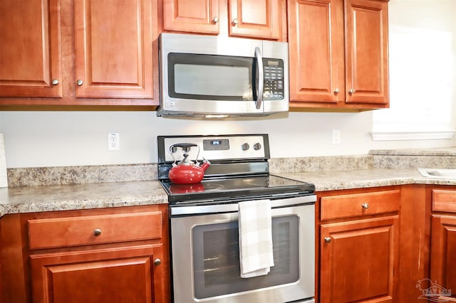 kitchen featuring brown cabinets, stainless steel appliances, and light countertops