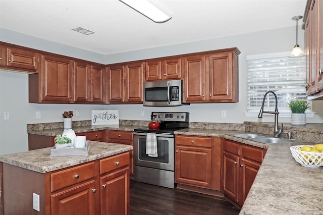 kitchen featuring dark wood-style floors, visible vents, appliances with stainless steel finishes, brown cabinetry, and a sink