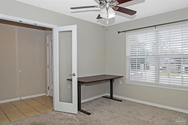 unfurnished office featuring carpet floors, baseboards, a ceiling fan, and tile patterned floors