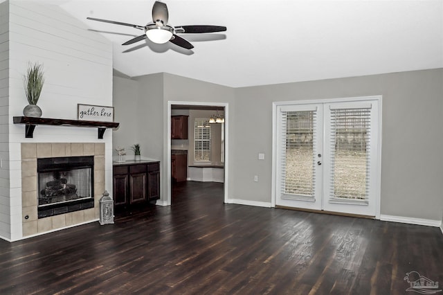 unfurnished living room featuring lofted ceiling, baseboards, dark wood-style flooring, and a tile fireplace