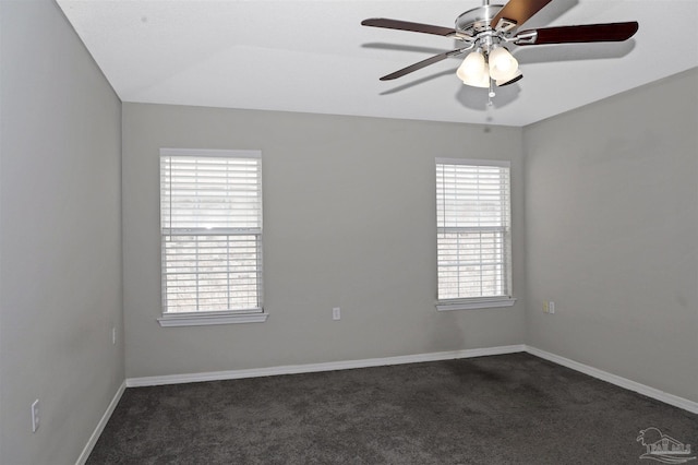 spare room with dark colored carpet, a ceiling fan, and baseboards