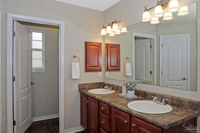 full bathroom featuring a sink, baseboards, and double vanity