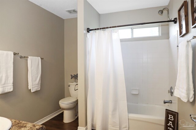 bathroom with baseboards, visible vents, toilet, wood finished floors, and shower / bathtub combination with curtain