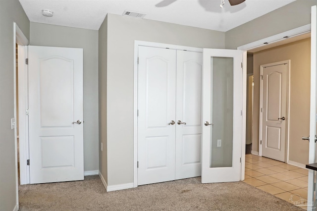 unfurnished bedroom with light tile patterned flooring, light colored carpet, visible vents, baseboards, and a closet