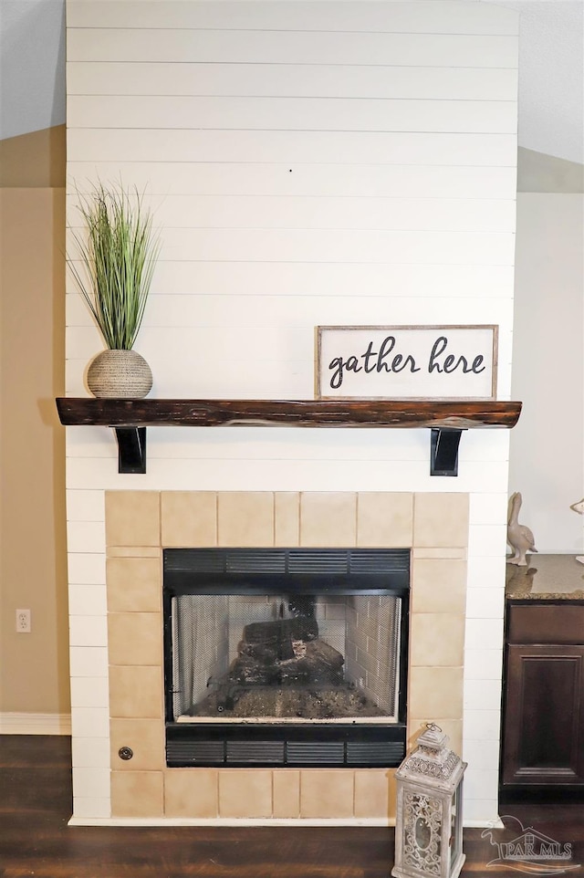 interior details featuring a tiled fireplace and wood finished floors