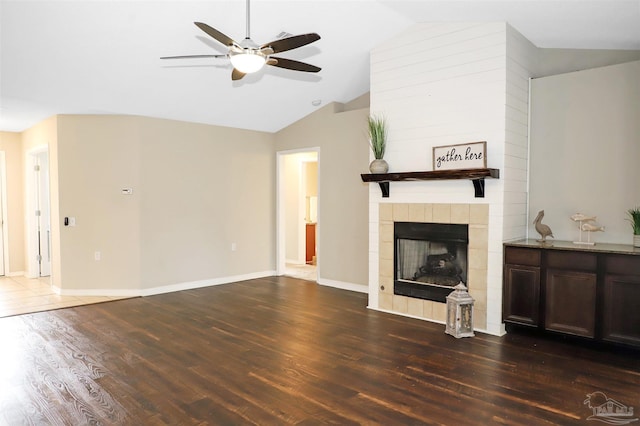 unfurnished living room with a tile fireplace, wood finished floors, a ceiling fan, baseboards, and vaulted ceiling