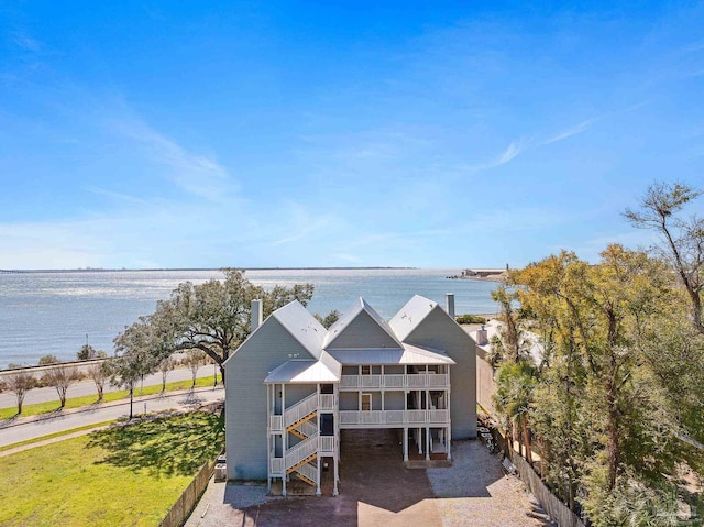 view of front facade featuring stairway, a water view, fence, and a balcony