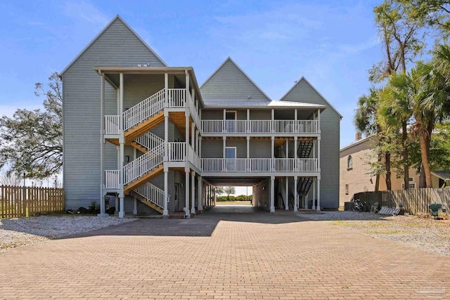 exterior space featuring a balcony, stairs, fence, decorative driveway, and a carport