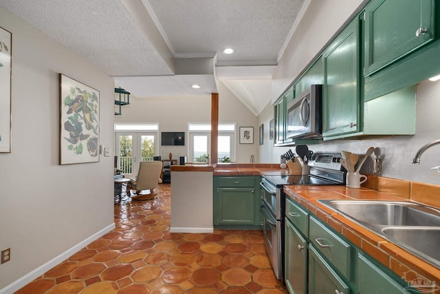 kitchen with green cabinetry, ornamental molding, a peninsula, stainless steel appliances, and a sink