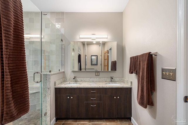 bathroom featuring a sink, a shower stall, baseboards, and double vanity