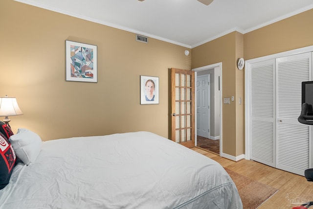 bedroom with light wood finished floors, baseboards, visible vents, crown molding, and a closet