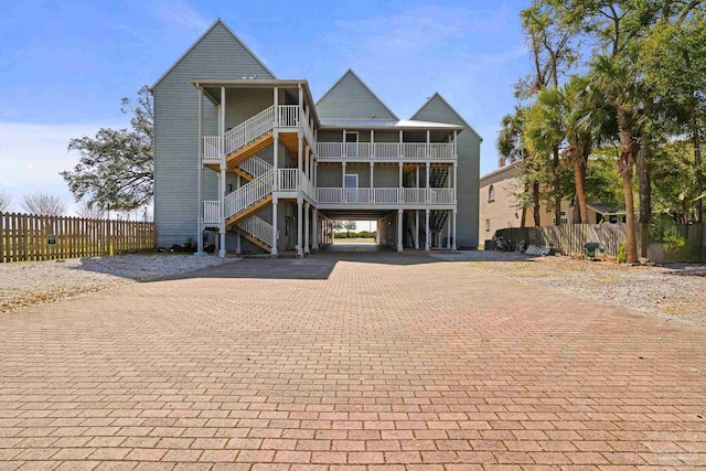 view of front facade with a balcony, stairway, fence, decorative driveway, and a carport