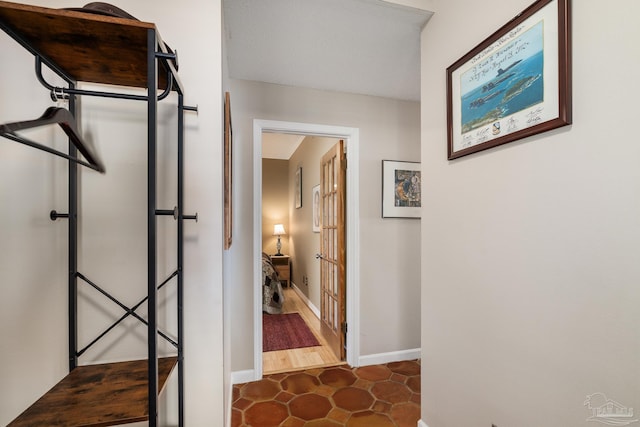 corridor with dark tile patterned flooring and baseboards