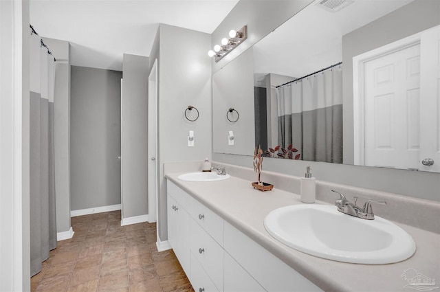 bathroom with visible vents, a sink, baseboards, and double vanity