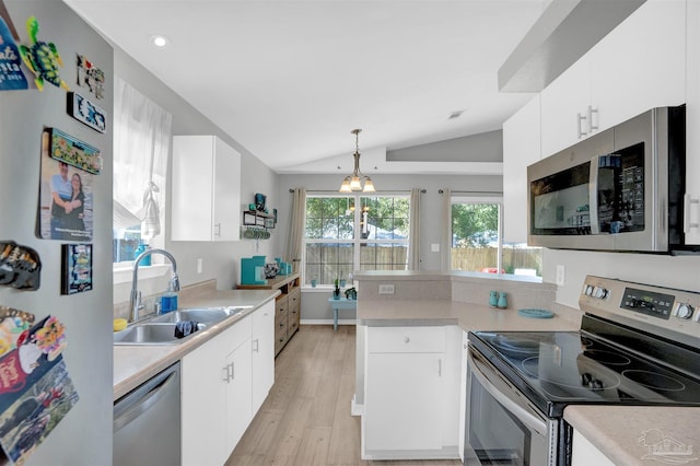 kitchen with stainless steel appliances, lofted ceiling, light countertops, a sink, and a peninsula