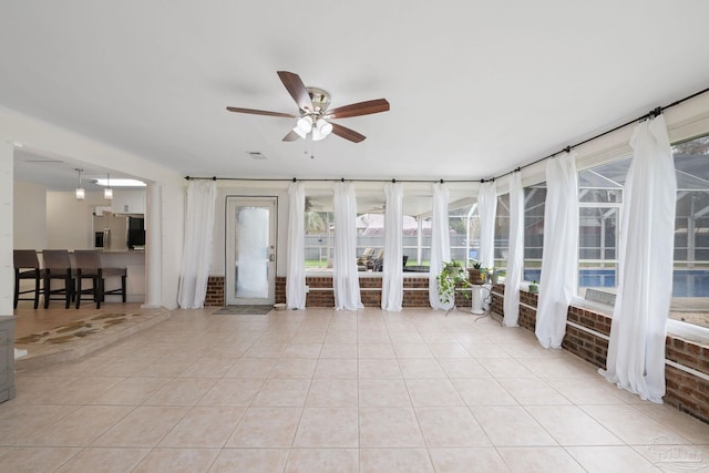 unfurnished sunroom featuring ceiling fan