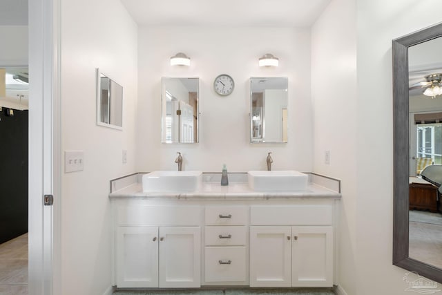 bathroom with double vanity, a sink, baseboards, and ensuite bathroom