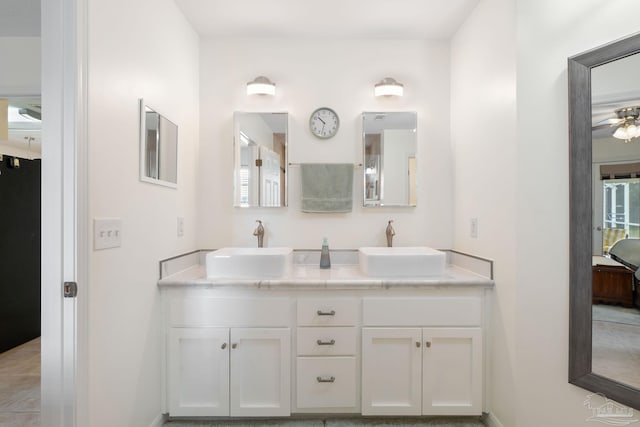 full bath with double vanity, ensuite bath, a sink, and baseboards