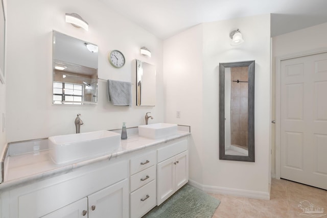 full bath with double vanity, tile patterned flooring, a sink, and baseboards