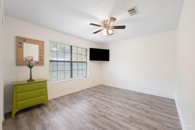 spare room featuring baseboards, light wood-style flooring, visible vents, and a ceiling fan