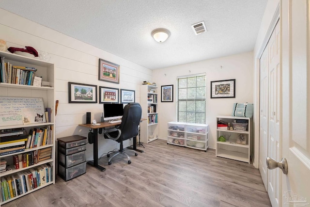 office with visible vents, a textured ceiling, and wood finished floors