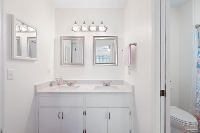 full bath featuring double vanity, a sink, and toilet