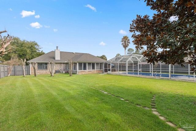 view of yard with a fenced in pool, glass enclosure, and fence