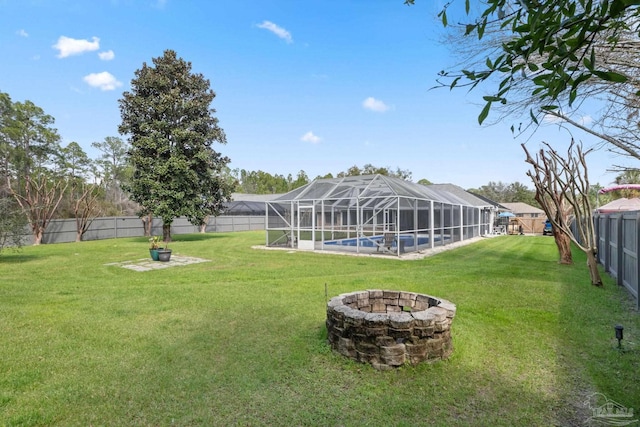 view of yard featuring glass enclosure, a fenced backyard, an outdoor pool, and a fire pit