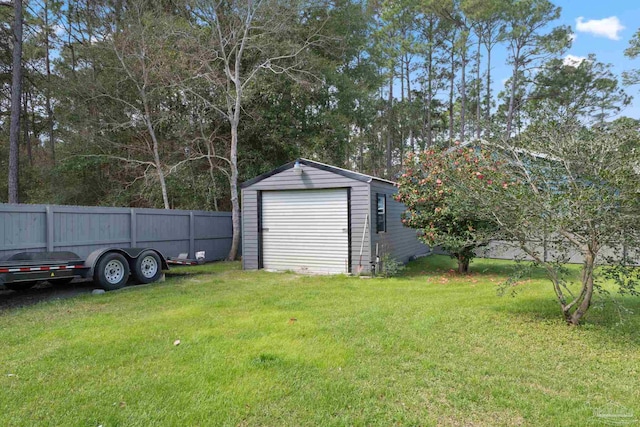 view of yard with a detached garage, fence, and an outbuilding