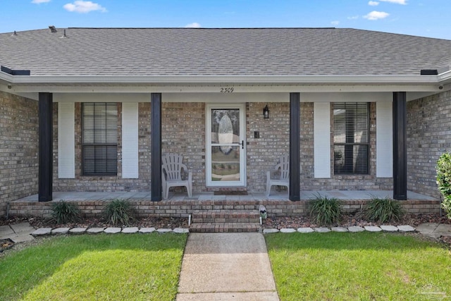 view of exterior entry featuring a porch and brick siding