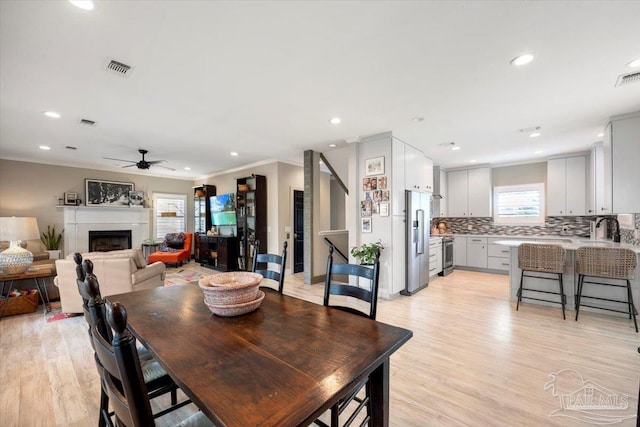 dining room featuring recessed lighting, a fireplace, light wood-style floors, and ornamental molding