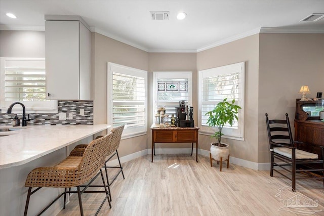 dining area featuring visible vents, light wood-type flooring, crown molding, and baseboards